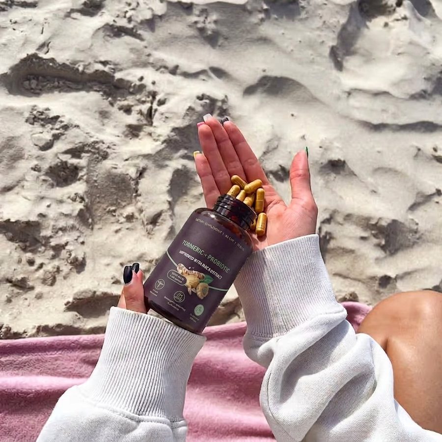 Turmeric + Probiotic bottle tipped over an open hand holding amber capsules